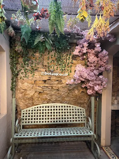 Pátio interno com banco e teto de flores e samambaias